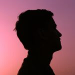 A striking silhouette of a man against a vibrant sunset sky, evoking a calm and introspective mood.